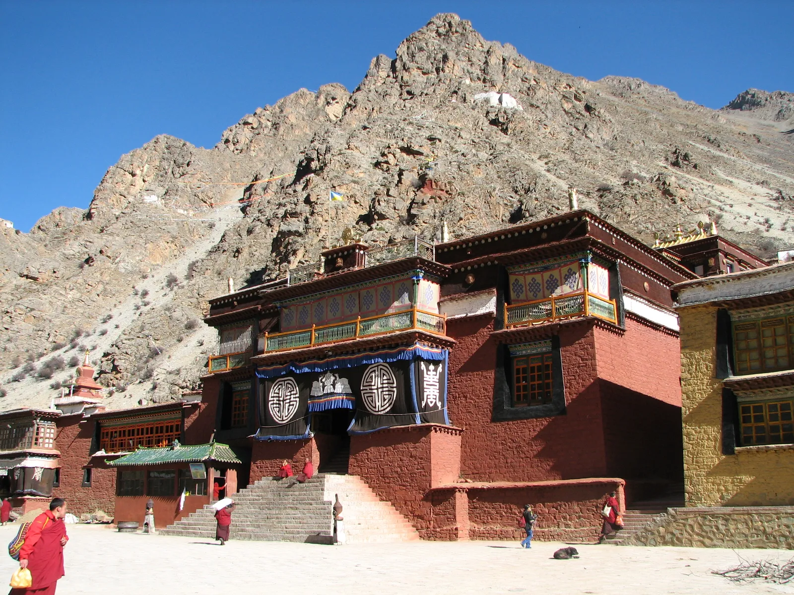 Assembly hall of Tsurphu Monastery below a rocky mountainside