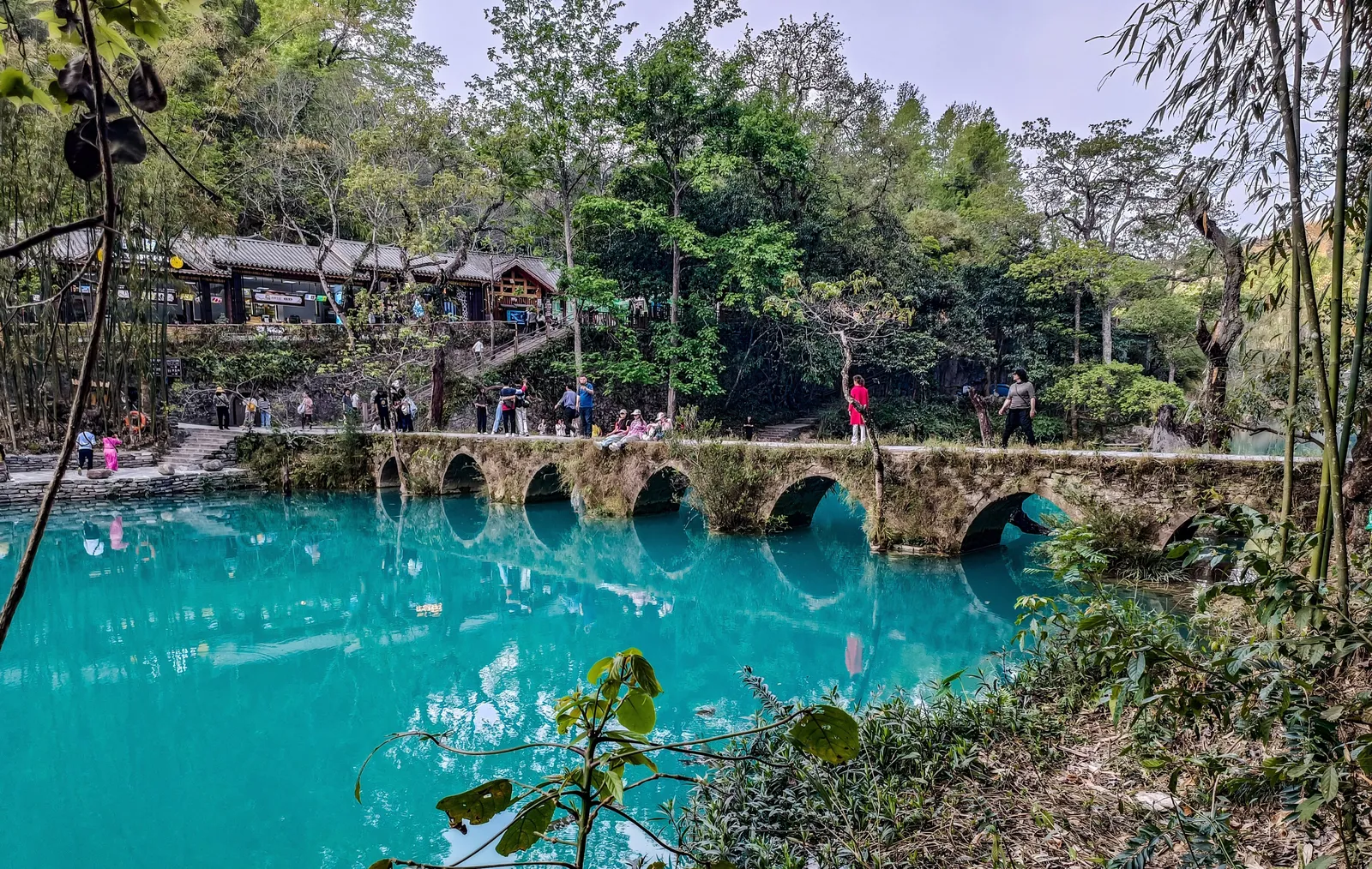 The old seven-arch stone bridge over turquoise water at Xiaoqikong, Libo