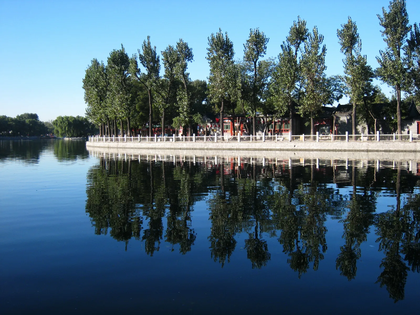 Willow-lined shore reflected in the still water of Shichahai lake