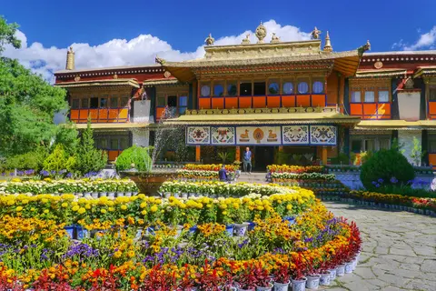 A palace in Norbulingka behind beds of bright flowers