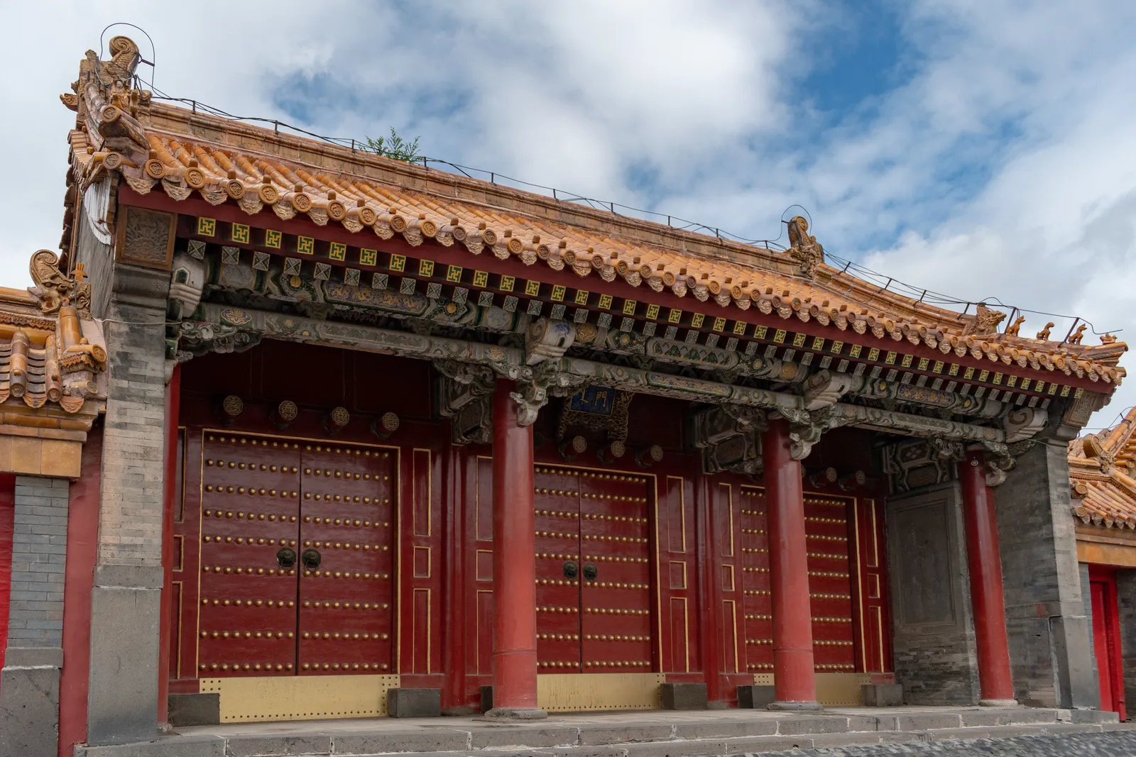Rotes Tor und bemalte Traufen einer Halle im Kaiserpalast Shenyang