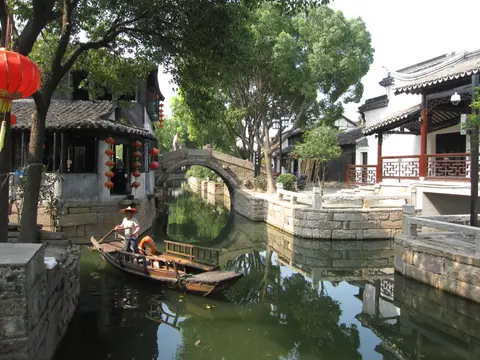 Rowing boat on a canal beneath a stone bridge in Luzhi