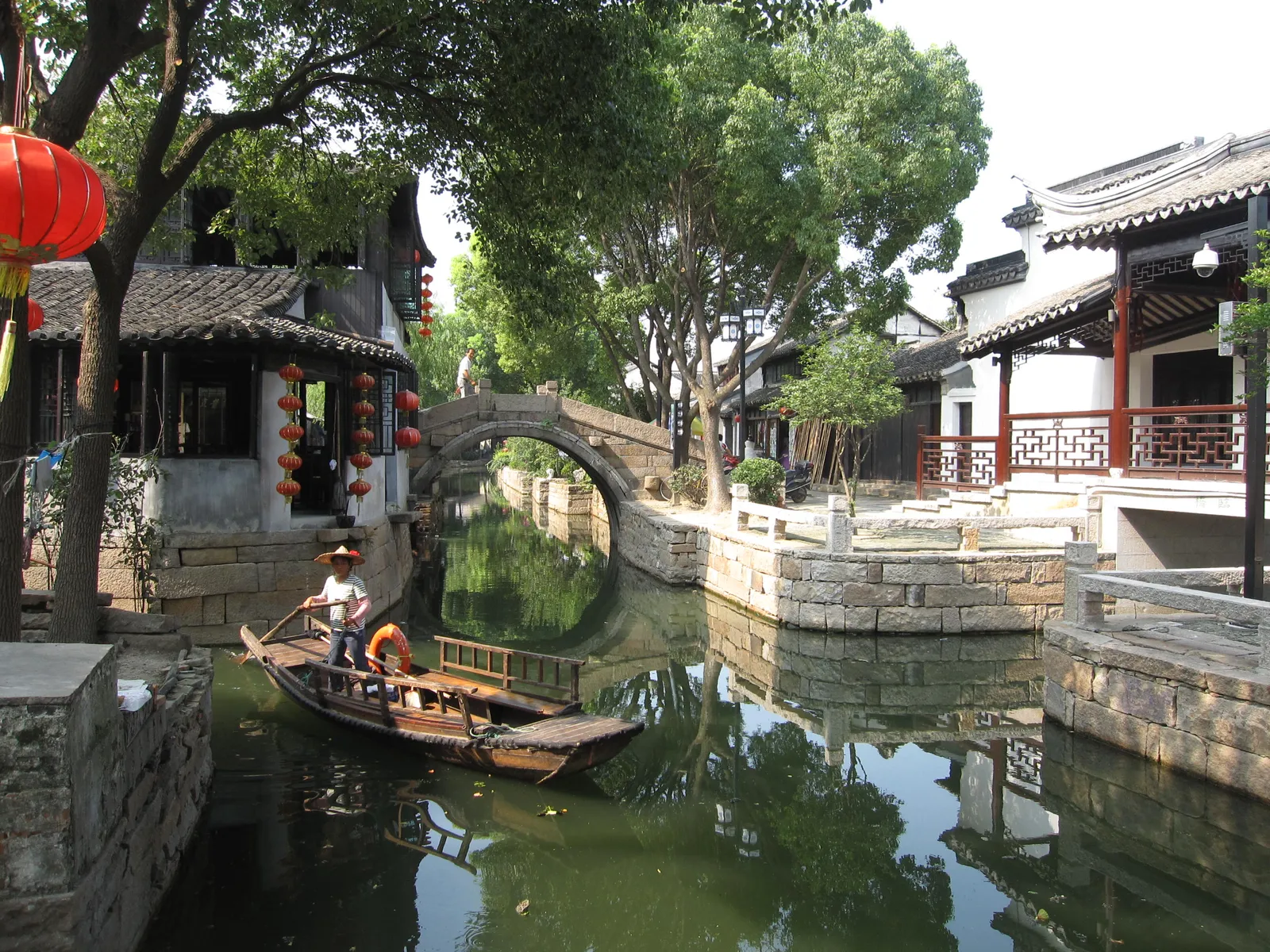 Rowing boat on a canal beneath a stone bridge in Luzhi