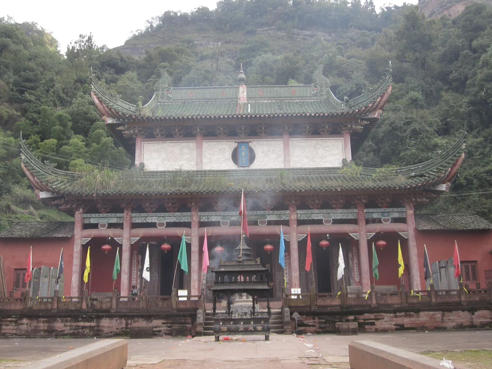 Taoist temple hall at the foot of forested cliffs on Mount Qiyun