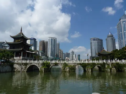 Jiaxiu Pavilion and its arched stone bridge on the Nanming River, with city towers behind