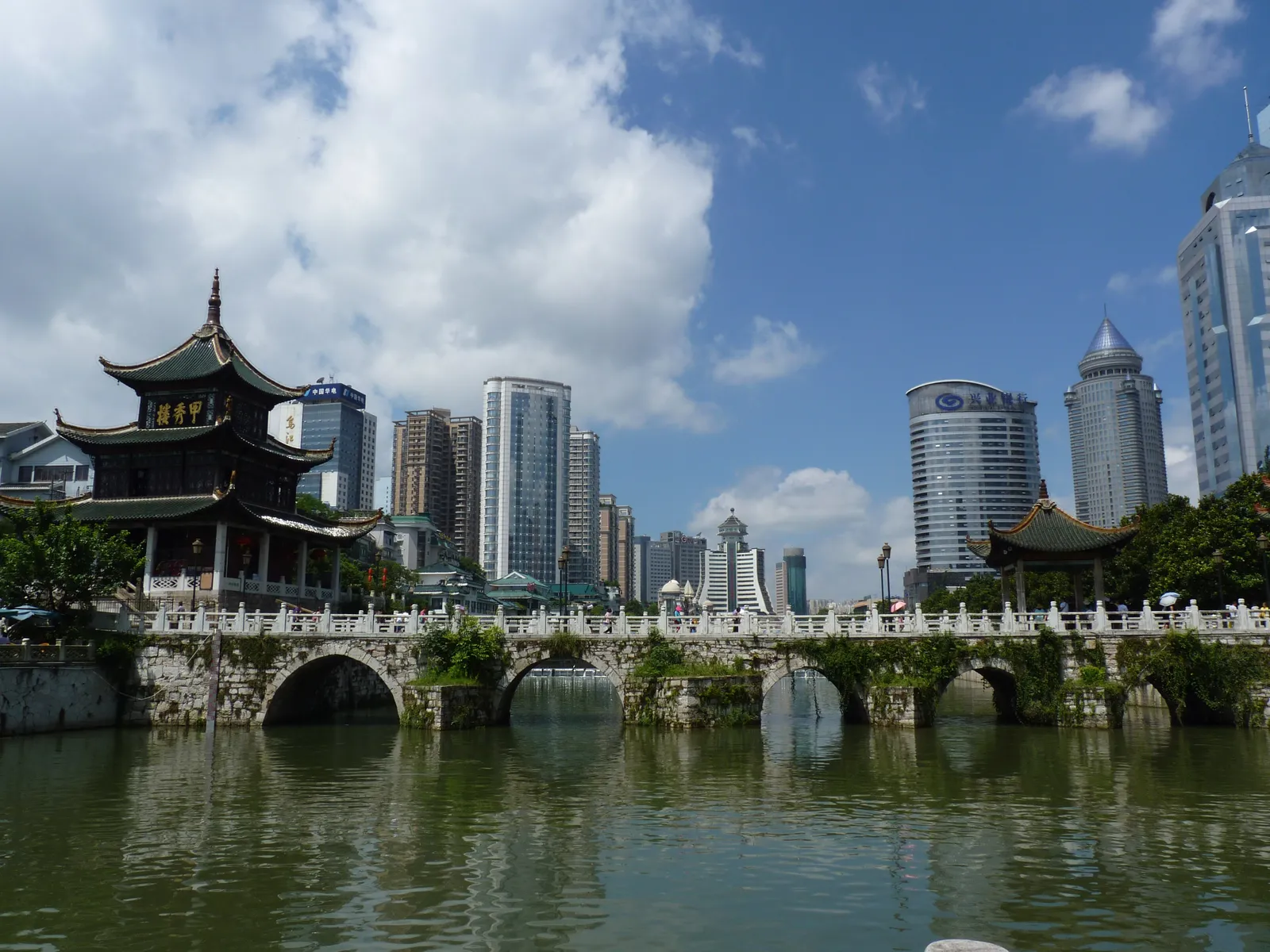 Jiaxiu Pavilion and its arched stone bridge on the Nanming River, with city towers behind