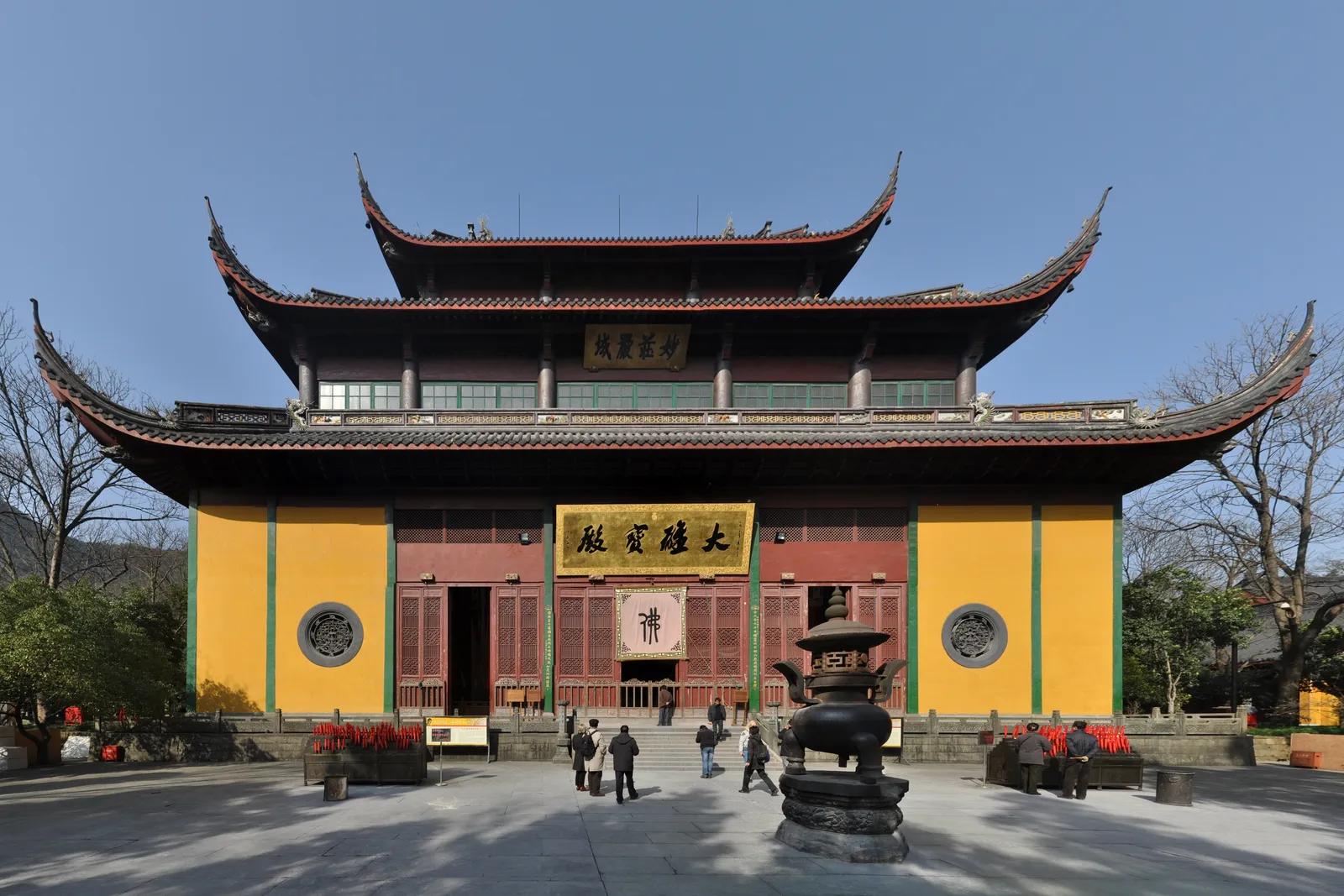 A yellow-walled hall at Lingyin Temple under a clear sky