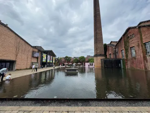 Old porcelain factory buildings and brick chimney around a pool at Taoxichuan