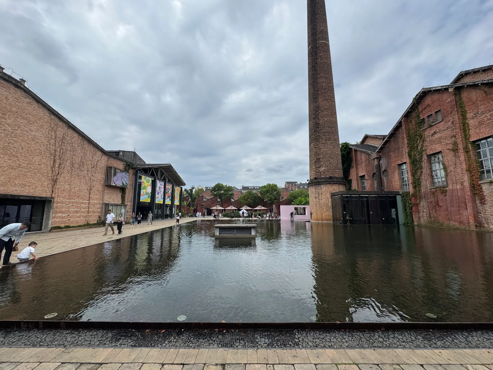 Old porcelain factory buildings and brick chimney around a pool at Taoxichuan
