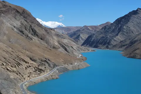 The turquoise waters of Yamdrok Lake between bare mountain slopes