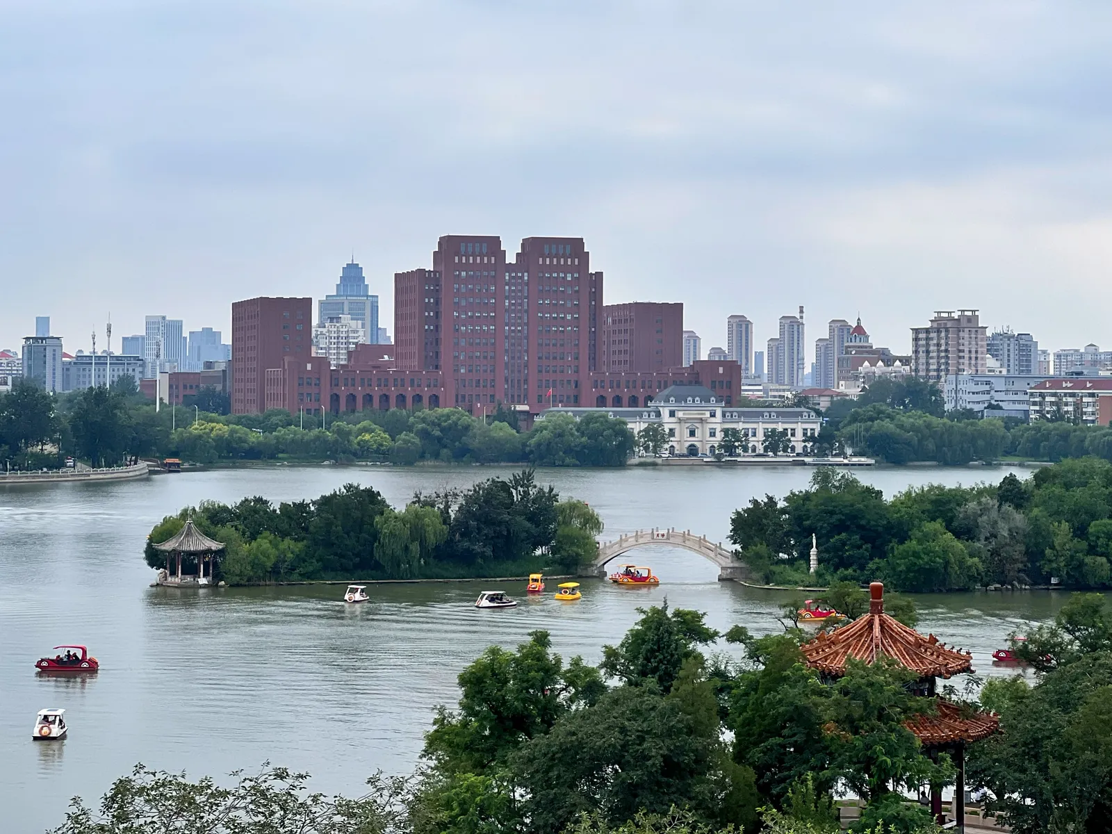 Pleasure boats around a wooded island on the West Lake of Tianjin Water Park
