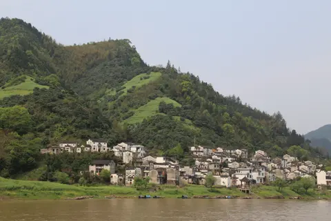 Village of white Huizhou houses on a green hillside along the Xin’an River