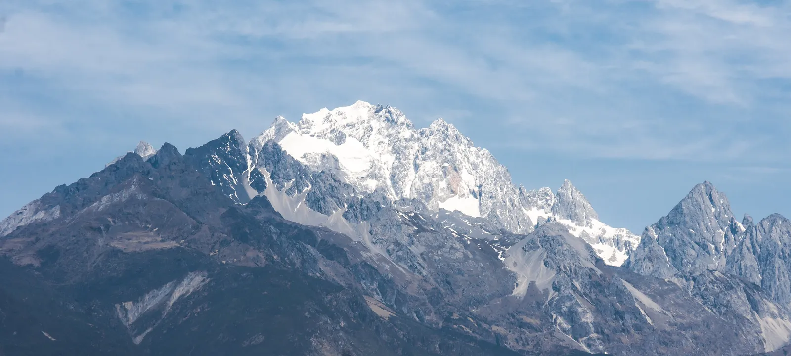 Snow-capped peaks of Jade Dragon Snow Mountain against a blue sky