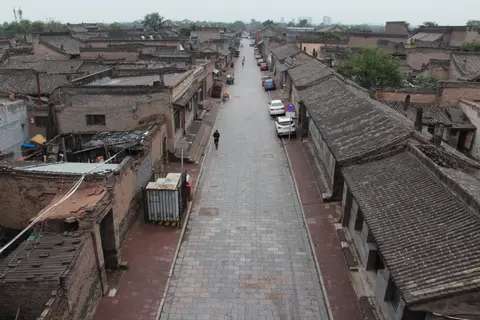 Grey-tiled rooftops and a straight street seen from the city wall