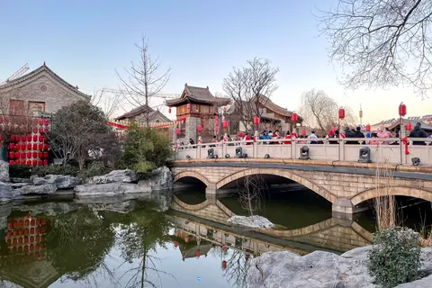 A stone bridge over a pond among traditional buildings in Luoyi Ancient City
