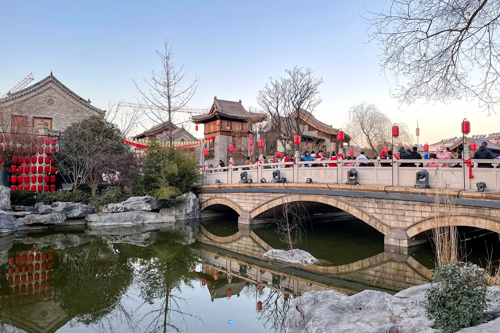 A stone bridge over a pond among traditional buildings in Luoyi Ancient City