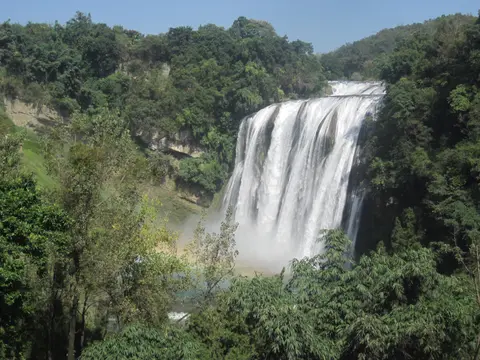 Huangguoshu Waterfall pouring over a green cliff under a blue sky