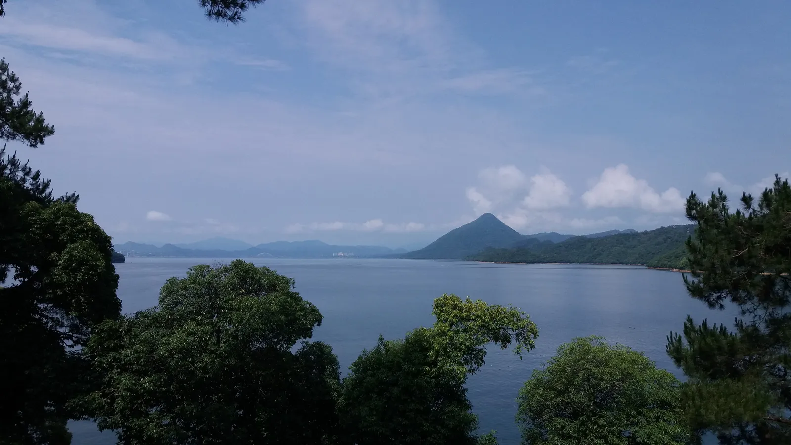 Taiping Lake’s calm water and wooded hills seen through trees