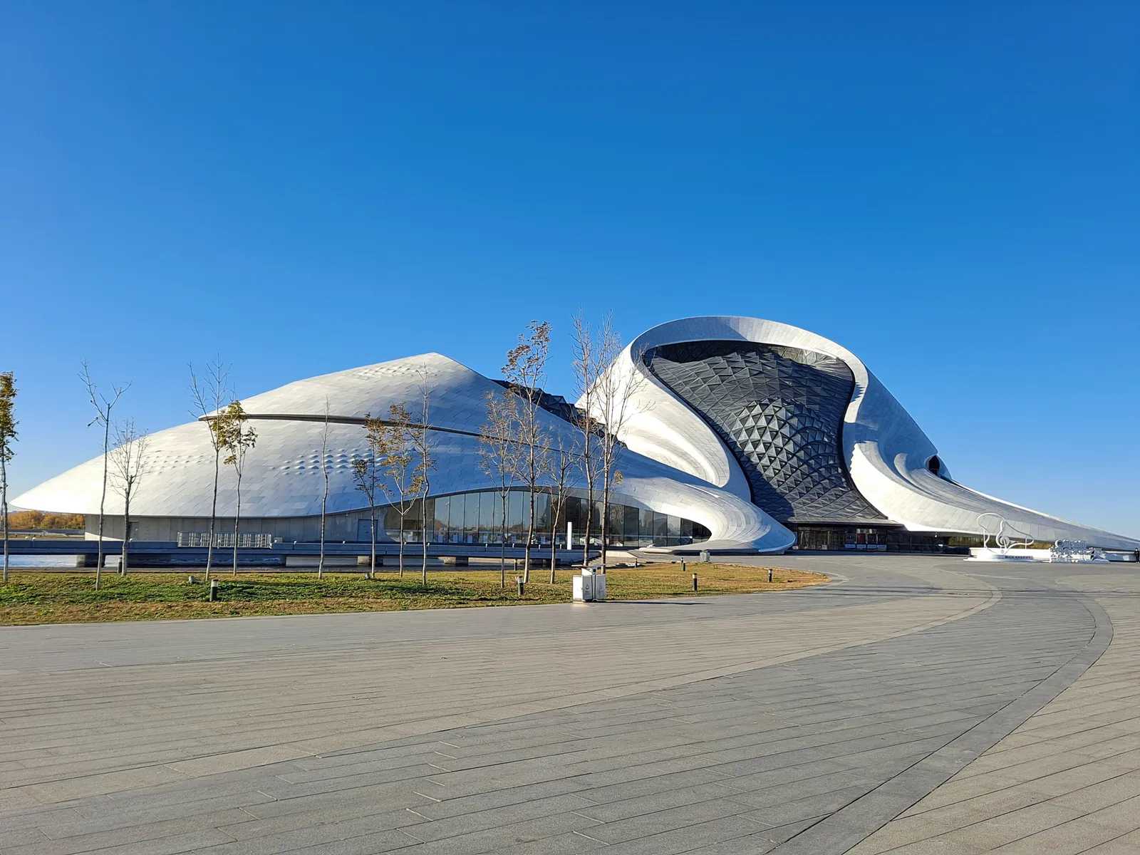 Curving white form of the Harbin Grand Theatre under a clear sky