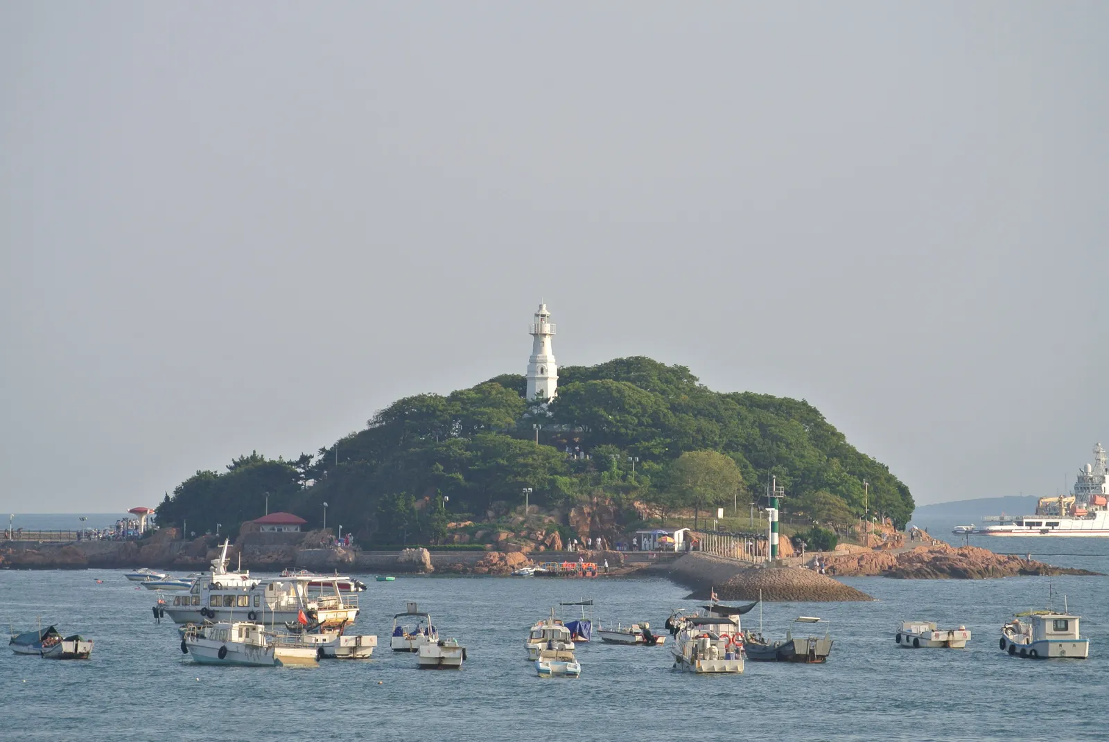 Little Qingdao Island with its white lighthouse, boats moored in front