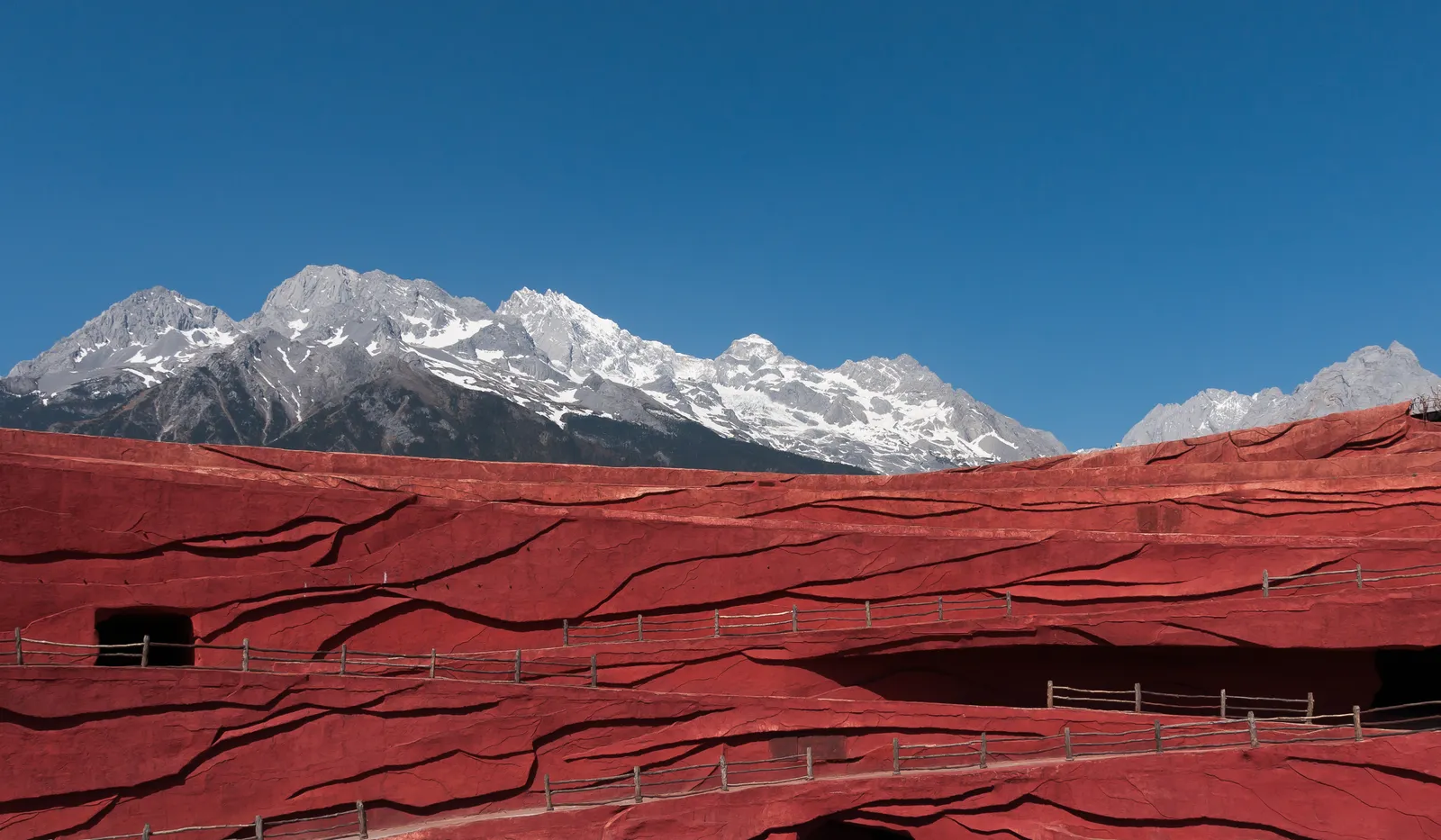 Red open-air stage of the Impression Lijiang theatre below the snow peaks