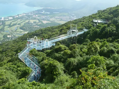 Glass skywalk winding over the forest with Yalong Bay in the distance