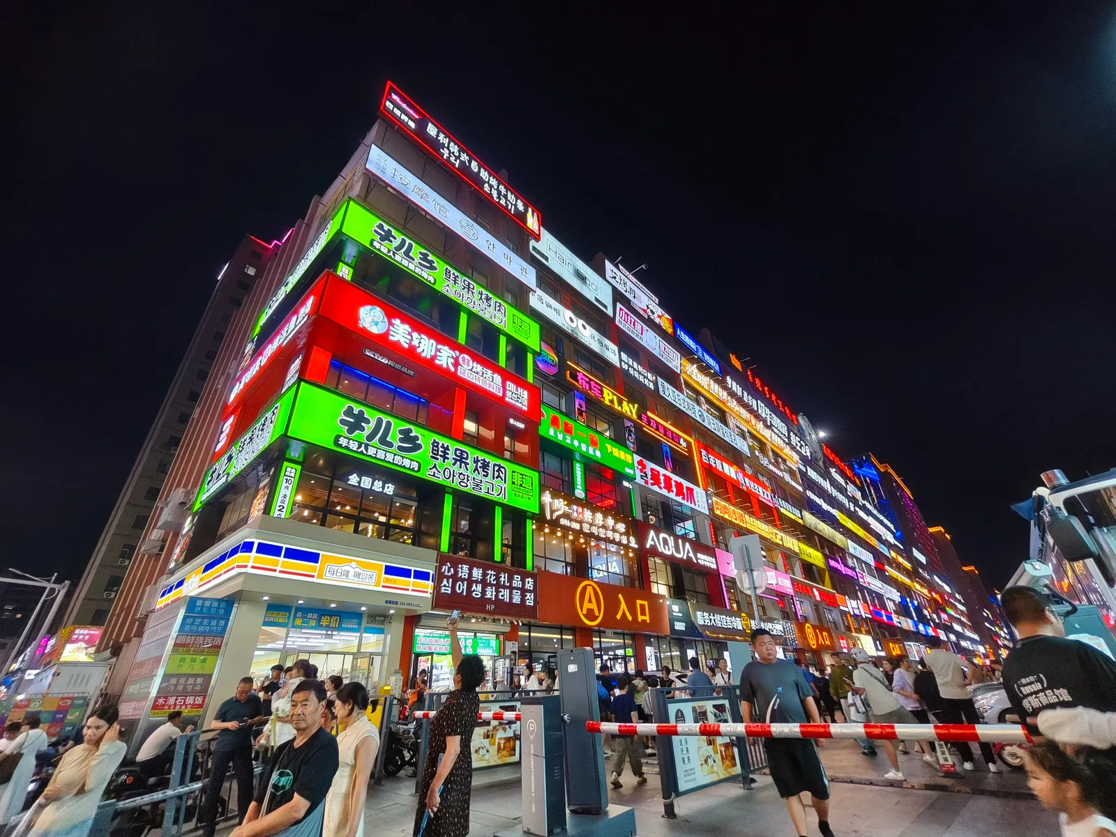Stacked neon shop signs in Chinese and Korean on the building opposite Yanbian University at night