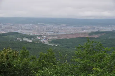 帽児山から森と畑の向こうに延吉を望む