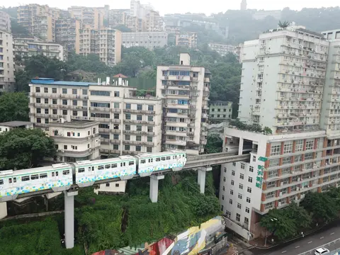 A monorail train passing through a residential building at Liziba Station