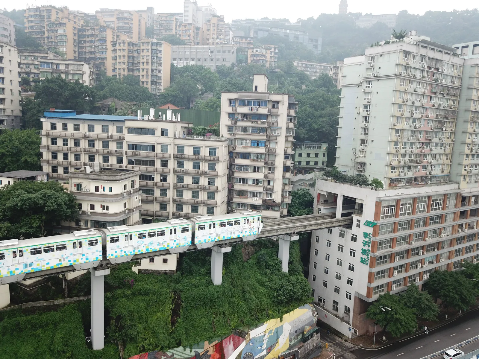 A monorail train passing through a residential building at Liziba Station