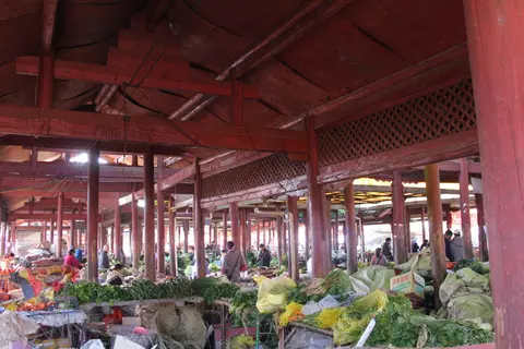 Produce stalls under the timber roof of a Lijiang food market