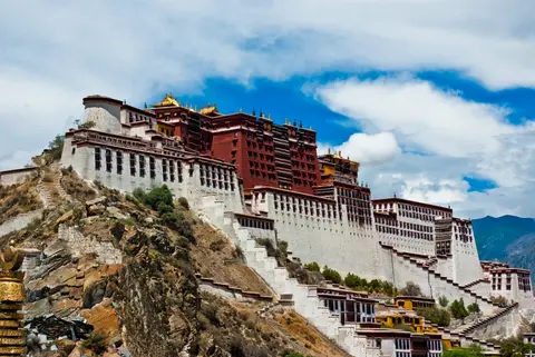 The white and red Potala Palace on Marpo Ri hill under a blue sky