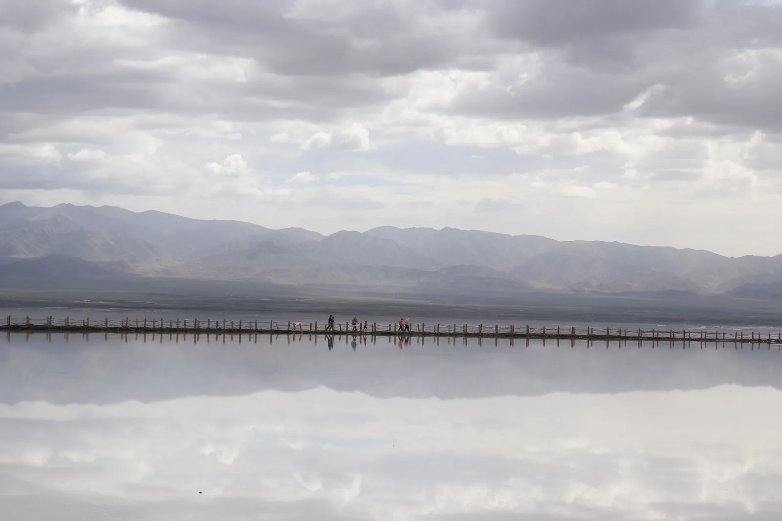 Mountains and clouds mirrored in the shallow water of Chaka Salt Lake
