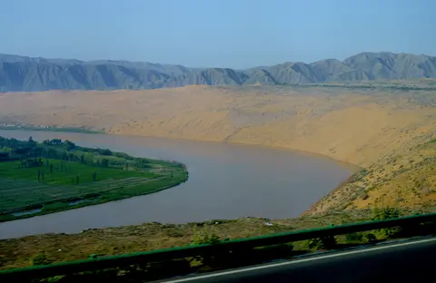 The Yellow River curving below the sand dunes at Shapotou