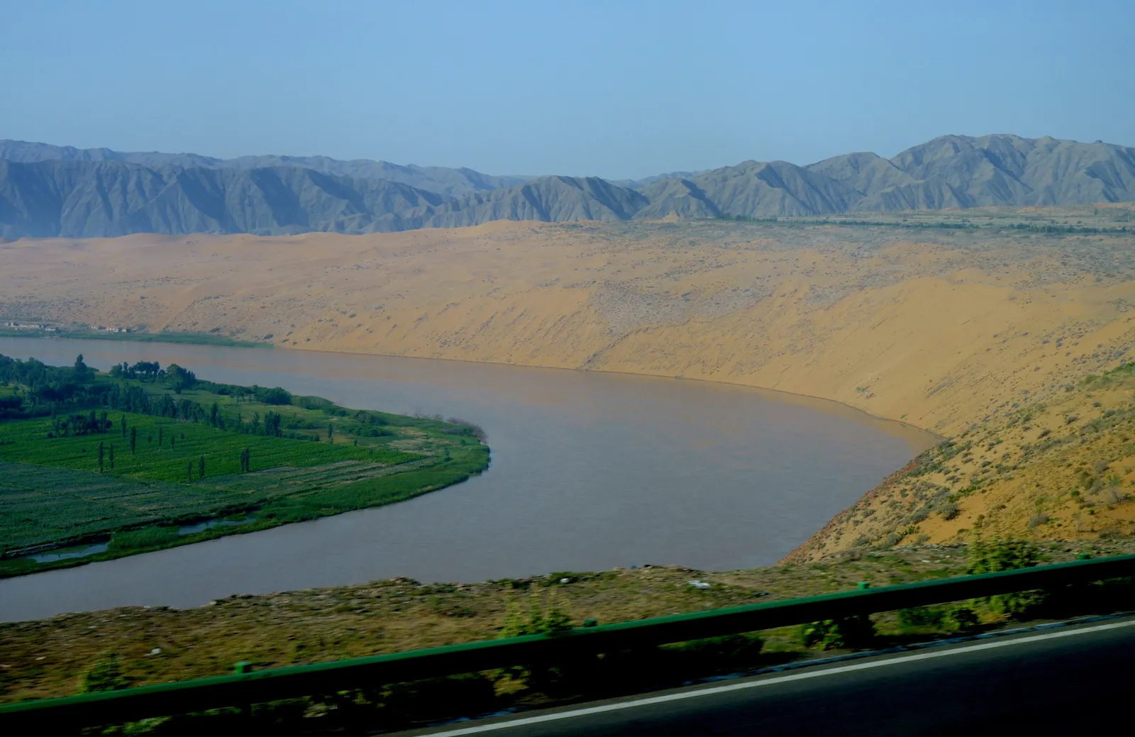 The Yellow River curving below the sand dunes at Shapotou