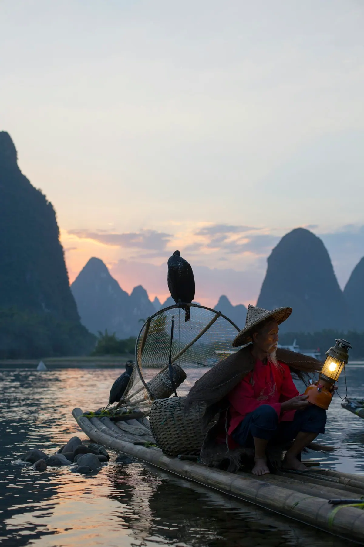 A cormorant fisherman on a bamboo raft among karst peaks